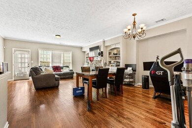 Dining area with a textured ceiling, dark wood-style flooring, ornamental molding, a chandelier, and built in shelves