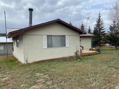 Rear view of house with a lawn, a metal roof, and a deck
