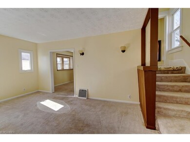Living room with dual staircase leading to kitchen