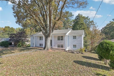 Back of house with a yard, brick siding, and view of scattered trees