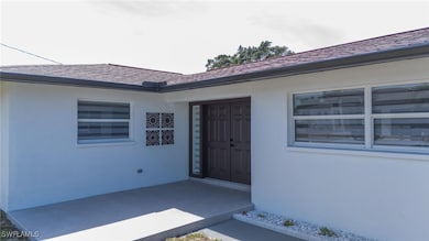View of exterior entry with stucco siding and a sh