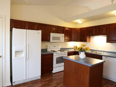 Kitchen. The kitchen features attractive cherry cabinets and laminate flooring, center island, and vaulted ceilings.