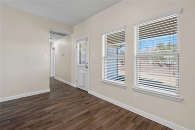 Spare room with baseboards and dark wood-type flooring