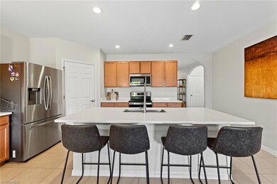 Kitchen featuring appliances with stainless steel finishes, light tile patterned flooring, recessed lighting, brown cabinets, and arched walkways