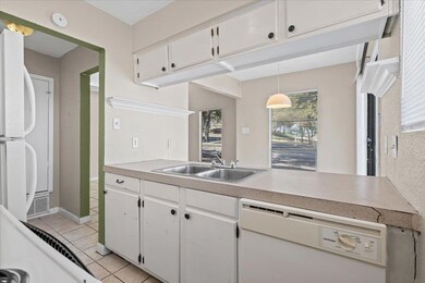 Kitchen with white cabinetry, white appliances, light countertops, and light tile patterned flooring