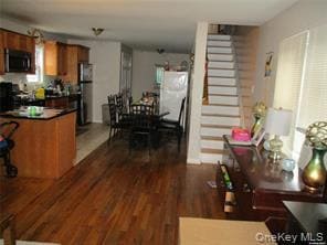 Kitchen with brown cabinetry, dark countertops, dark wood-type flooring, and stainless steel microwave