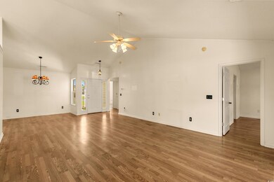 Unfurnished living room with high vaulted ceiling, ceiling fan with notable chandelier, baseboards, and wood finished floors