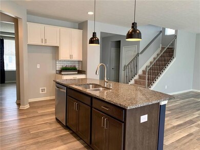 Kitchen features pendant lighting, granite counters and stainless appliances. 