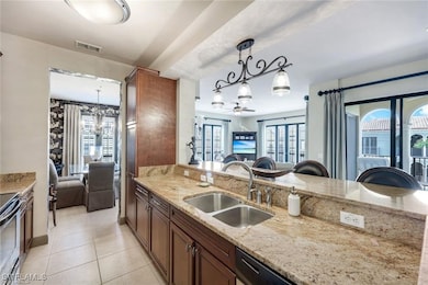 Kitchen featuring light stone countertops, pendant lighting, light tile patterned floors, a chandelier, and stainless steel range with electric stovetop