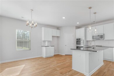 Kitchen with stainless steel appliances, decorative backsplash, white cabinetry, a chandelier, and recessed lighting