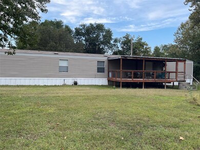 Back of property featuring a wooden deck and a yar