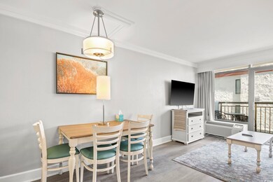 Dining area with a wall mounted air conditioner, wood finished floors, crown molding, and baseboards