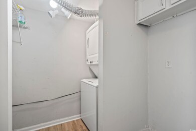 Washroom featuring stacked washer / dryer, cabinet