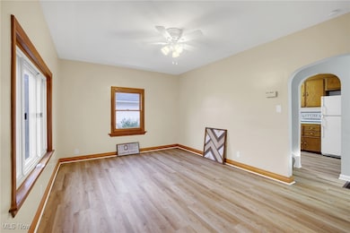 Spare room with arched walkways, light wood-style floors, plenty of natural light, and a ceiling fan