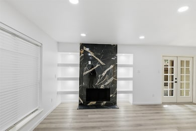 Unfurnished living room with light wood finished floors, recessed lighting, and french doors