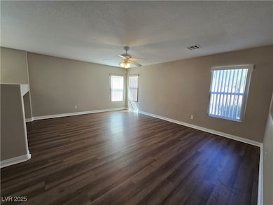 Empty room featuring dark wood-type flooring, a textured ceiling, and ceiling fan
