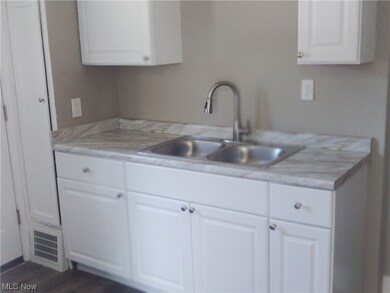 Kitchen featuring dark hardwood flooring, light countertops, and white cabinets