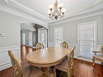 Dining area featuring plenty of natural light, crown molding, a tray ceiling, arched walkways, and dark wood-style floors