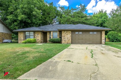 Single story home featuring a garage, driveway, brick siding, and a front lawn