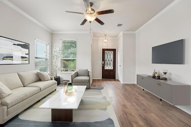 Living room with wood finished floors, a ceiling fan, crown molding, and baseboards