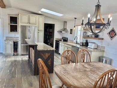 Dining area featuring wine cooler, vaulted ceiling with skylight, hardwood / wood-style flooring, and an inviting chandelier