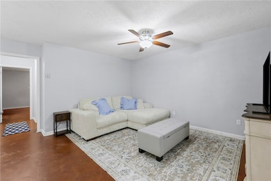 Living room with ceiling fan, concrete floors, and