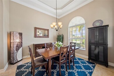 Large formal dining room with tile floor, tall ceiling, crown molding, tray ceiling, arched openings, and window blinds.