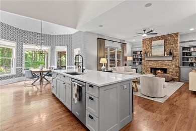 This stunning, fully renovated kitchen features high-end finishes including a Wolf cooktop, double ovens, quartz countertops, soft-close cabinetry, an oversized island, and a spacious walk-in pantry. It opens beautifully to the vaulted breakfast area