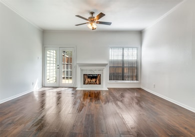 Unfurnished living room with a fireplace, healthy amount of natural light, dark wood-style floors, and ornamental molding