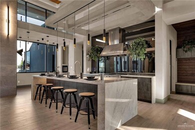 Kitchen with an island with sink, hanging light fixtures, a breakfast bar, a towering ceiling, and light wood-type flooring
