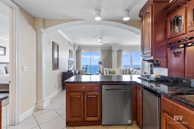 Kitchen with open floor plan, stainless steel dishwasher, a peninsula, light tile patterned floors, and a ceiling fan