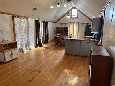 Kitchen featuring freestanding refrigerator, a ceiling fan, vaulted ceiling, light wood finished floors, and a peninsula