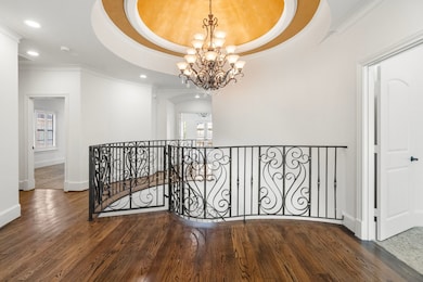 A view of the upstairs landing featuring hardwood flooring and the continuation of the custom railing, complete with matching safety gates at the top and bottom of the stairs.
