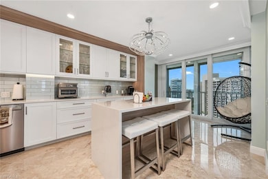 Kitchen with marble finish floor, light countertops, stainless steel dishwasher, decorative backsplash, and white cabinetry