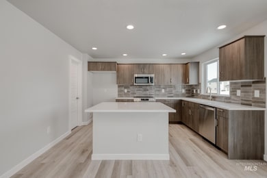 Kitchen with modern cabinets, a kitchen island, backsplash, appliances with stainless steel finishes, and recessed lighting