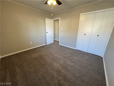 Bedroom with dark carpet, a ceiling fan, ornamental molding, and a closet