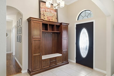 Entryway with arched walkways, crown molding, a chandelier, and light tile patterned flooring