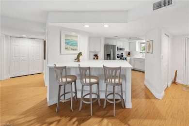 Kitchen with a peninsula, light countertops, light wood-style floors, recessed lighting, and white cabinetry