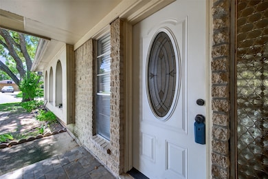 This charming entryway features a
white door with an oval glass insert,
framed by textured brick walls. A small
window adds light, while tiled flooring
and gentle lighting create a warm,
inviting welcome.
