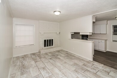 Unfurnished living room with ornamental molding, a textured ceiling, wood tiled floors, and a fireplace