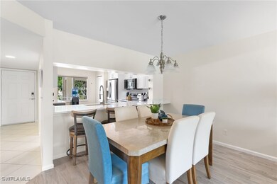 Dining space with light wood look tile floors and a chandelier