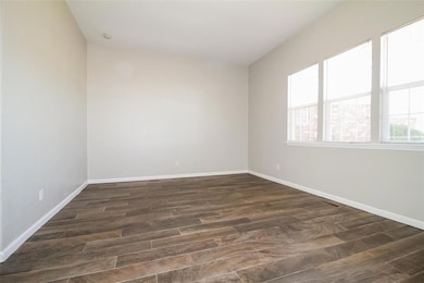 Empty room with dark wood-style flooring and baseboards