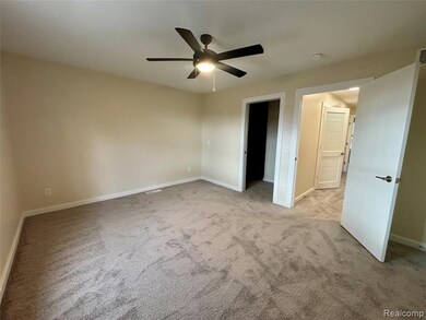 Unfurnished bedroom with light colored carpet, ceiling fan, and a walk in closet