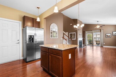 Kitchen featuring hanging light fixtures, stainless steel refrigerator with ice dispenser, a center island, and light stone counters