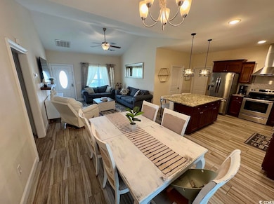 Dining space with lofted ceiling, wood finished floors, a chandelier, a ceiling fan, and baseboards