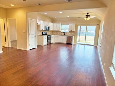 Kitchen with lofted ceiling, backsplash, sink, appliances with stainless steel finishes, and white cabinets