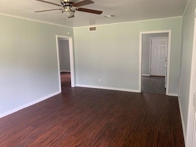 Unfurnished room featuring ceiling fan, dark hardw