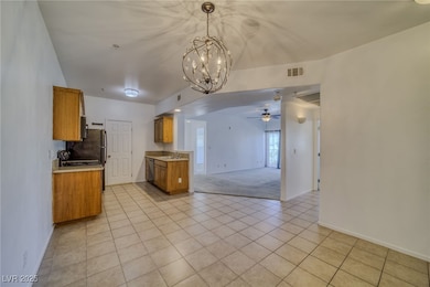 Kitchen featuring light tile patterned floors, brown cabinetry, open floor plan, and a chandelier