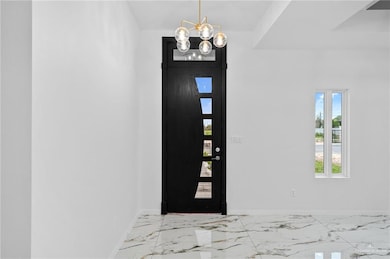 Entryway with baseboards, marble finish floor, and a notable chandelier