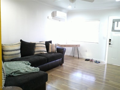 Living area featuring a wall unit AC, crown moldin